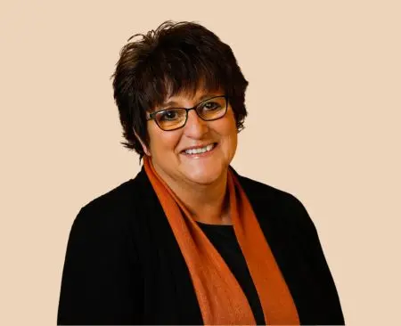 woman smiling wearing a black top with orange scarf