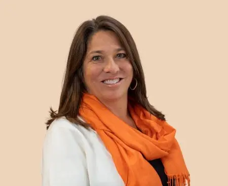 woman smiling wearing white cardigan over a black top with orange scarf