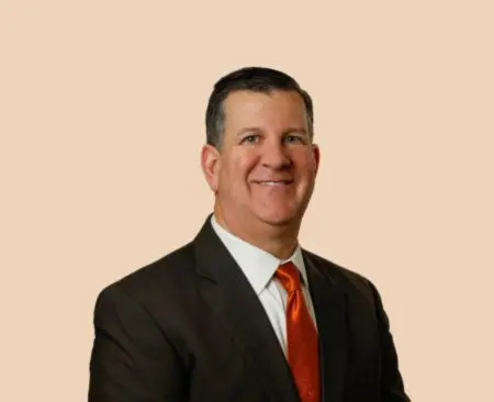 smiling man in black suit jacket with orange tie