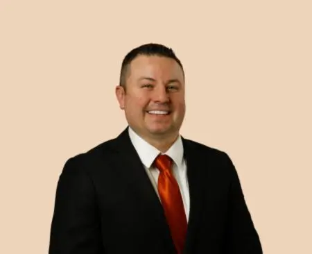 smiling man in black suit jacket with orange tie