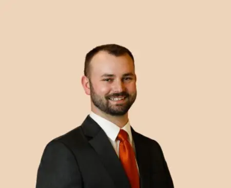 smiling man in black suit jacket with orange tie