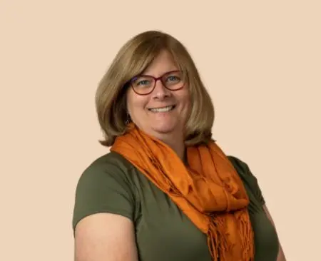 smiling woman with short hair in an olive green blouse an orange scarf