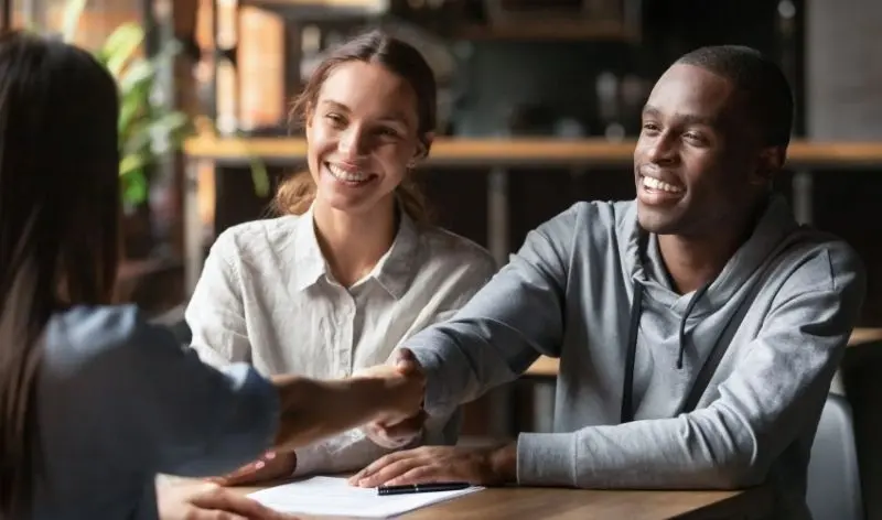 people at a desk shaking hands