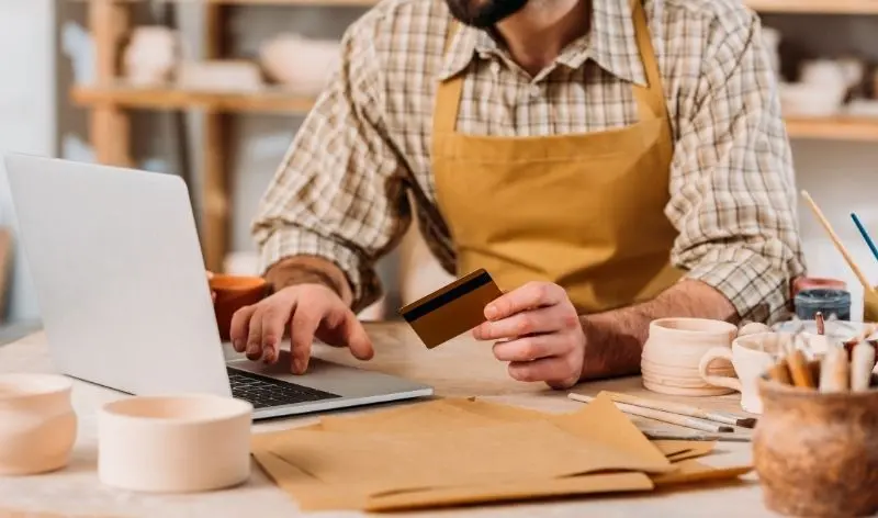 man holding card while typing on laptop