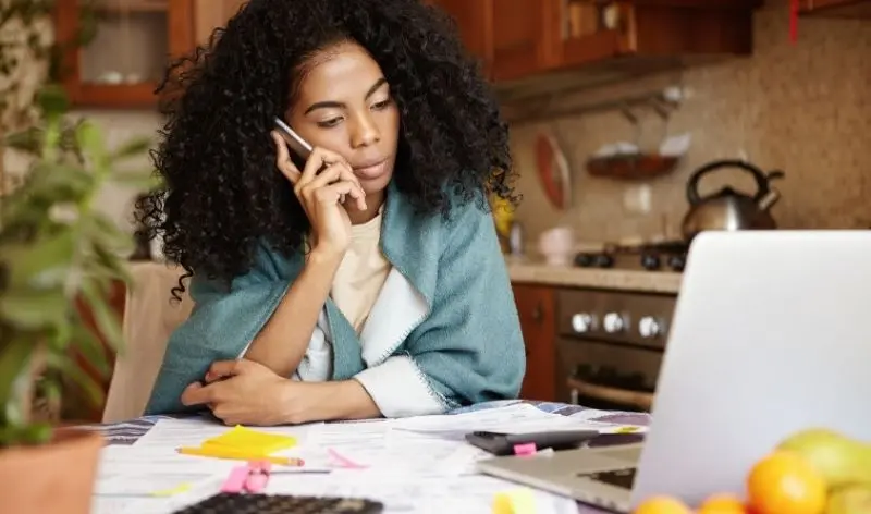 person looking at a laptop while on a phone call