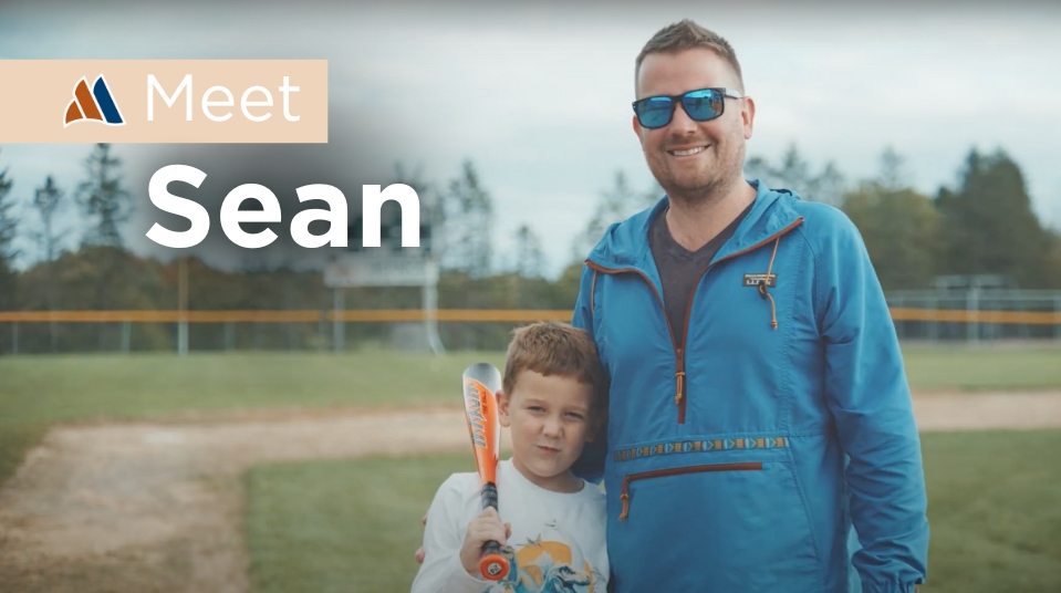 Sean standing on a baseball field with a child