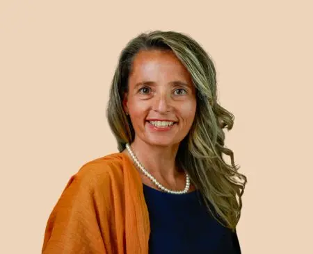 woman smiling wearing black top and orange shawl with white pearl necklace