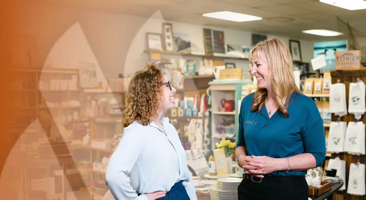 Two women in a gift shop smiling at each other