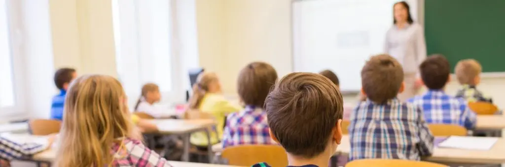 Children sitting at desks looking at their teacher