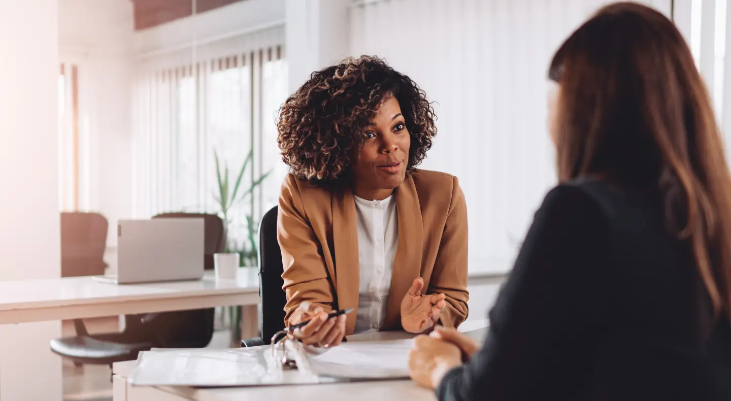 two women sitting at a table having a conversation