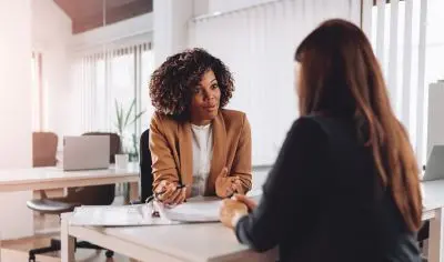 woman sitting down at desk with client.