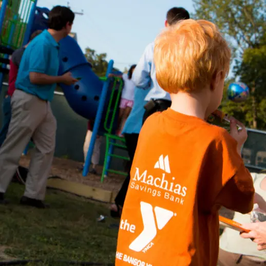 little boy in organge t-shirt standing on playground