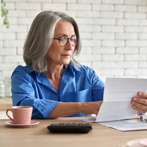 older woman sitting down at a table looking at a billing statement