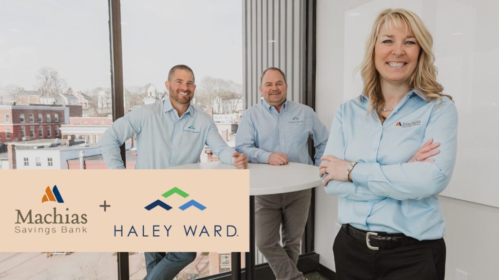 woman business banker smiling with two business owners in background smiling